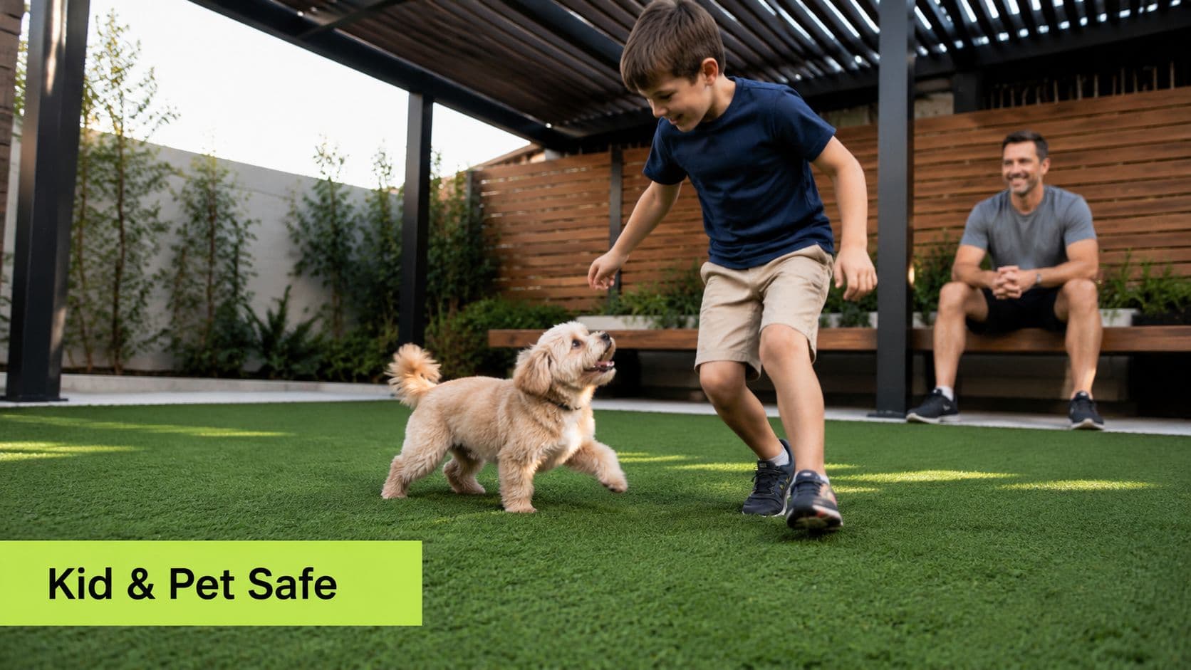 A young boy playing with a small puppy on a lush green artificial turf lawn outdoors.